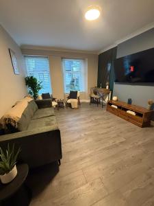 a living room with a couch and a flat screen tv at Vacant Nests Ivy Cottage 3BR Wi-Fi in Banton