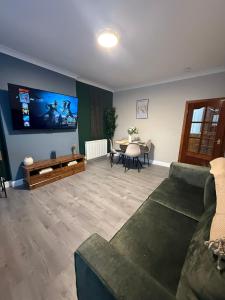 a living room with a couch and a tv at Vacant Nests Ivy Cottage 3BR Wi-Fi in Banton