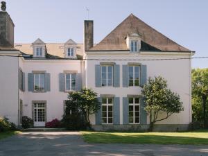 a large white house with blue shutters at Domaine de Kermadio in Pluneret