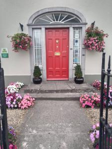 uma porta vermelha da frente de uma casa com flores em Townsend House Guest House em Birr