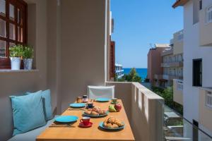 a table with plates of food on a balcony at Nissos Home by Prime Stay in Hersonissos