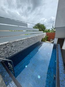 a swimming pool next to a building with a brick wall at Lanka Villa Mirissa in Mirissa