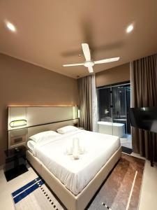 Genting Antara Residence, Covered Link Bridge access to Genting Highlands في مرتفعات جنتنغ: غرفة نوم مع سرير أبيض كبير مع مروحة سقف