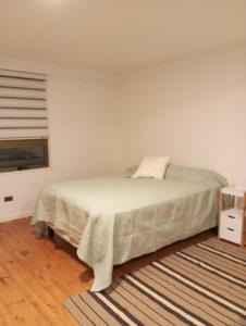 um quarto branco com uma cama e uma janela em Oceana Suites en Algarrobo em San Antonio