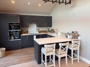 a kitchen with black cabinets and a kitchen island with stools at Four Seasons Lodge in Lichfield