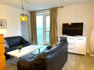 a living room with a leather couch and a television at Oasen Samsø in Nordby