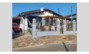 una casa bianca con un cancello davanti di Kitnet mobiliado da Nice - FUNDOS a Guaíba