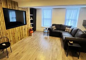 een woonkamer met een leren bank en een flatscreen-tv bij Williamson Suites - Apartment 2 in Liverpool