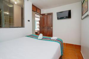 Schlafzimmer mit einem Bett, einem Spiegel und einer Tür in der Unterkunft Inkary Hotel Machupicchu in Machu Picchu