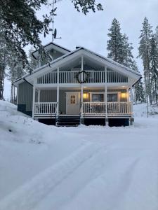 a house in the snow with lights on it at Villa Hyppykallio, LaatuLomat in Juva