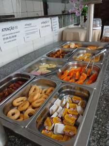 ein Buffet mit verschiedenen Speisen in Tabletts in der Unterkunft Hotel Silveira in Guarapari