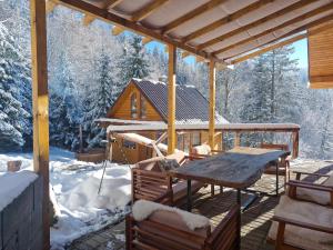 a porch with a wooden table and a house in the snow at Chaty Jelenye in Turzovka