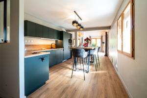 een keuken met blauwe kasten en barkrukken bij Chalet Le cocon plein sud in Saint-Chaffrey