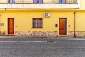 ein gelbes Gebäude mit drei Türen an einer Straße in der Unterkunft Casa Lia in Monastir