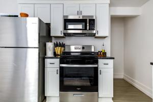 una cucina con armadi bianchi e forno nero di Short North Convention King Bed Free Parking! a Columbus