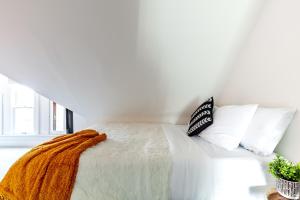 un letto bianco con una coperta arancione e cuscini di Short North Convention King Bed Free Parking! a Columbus