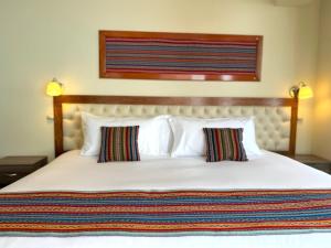 a bedroom with a large white bed with two pillows at Hotel Chinchero Boutique & Tours in Chinchero