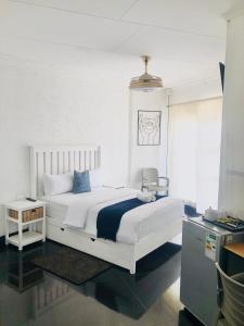 2 Seasons Guesthouse East London في شرق لندن: غرفة نوم بسرير ابيض ومكتب