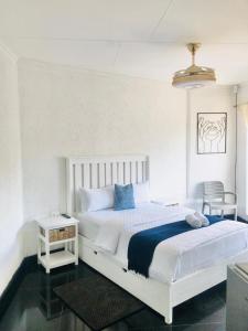 2 Seasons Guesthouse East London في شرق لندن: غرفة نوم بها سرير أبيض كبير وطاولة