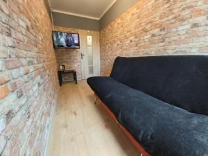 a couch in a room with a brick wall at 2051 Zwycięstwa 23 - Tanie Pokoje - samodzielne zameldowanie - self check in in Poznań +24 photos