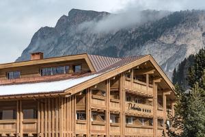 une maison en bois avec une montagne en arrière-plan dans l'établissement Hotel Garni Dolomieu, à Selva di Val Gardena