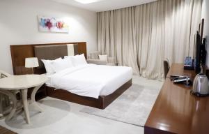Un dormitorio con una cama, una mesa y un escritorio. en إس بي واي للشقق المخدومة - SBY Serviced Apartments, en Buraidah