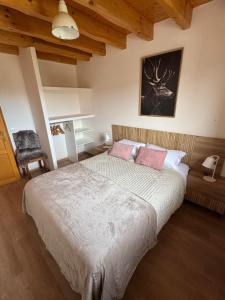 ein Schlafzimmer mit einem großen Bett mit zwei rosa Kissen in der Unterkunft CAL QuEROL UR casa amb xemeneia i billar in Ur