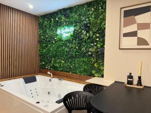 a bath tub with a green wall in a room at La suite Nova - Jacuzzi in Valenciennes +25 photos