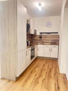 a kitchen with white cabinets and a wooden floor at Suite Fortuna in Mainz-Kostheim