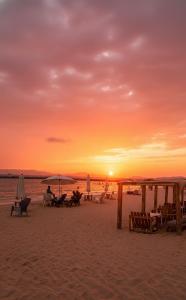 a sunset on the beach with tables and umbrellas at Exclusivo Apartamento en Lecherías 1 min caminando hasta la playa in El Morto de Barcelona
