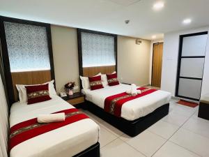 a hotel room with two beds with red and white sheets at Elite Hotel KL Sentral in Kuala Lumpur