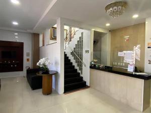 a lobby with a staircase and a table with flowers at Mais Hotel Express in São Luís