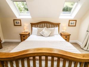 a bedroom with a large bed with two windows at The Coach House in Carnforth