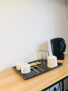 2 Seasons Guesthouse East London في شرق لندن: صينية مع أكواب وآلة صنع القهوة على منضدة +20 صورة