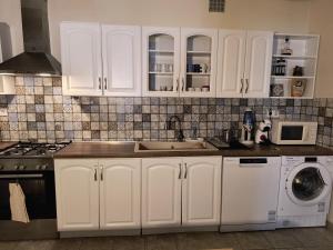 una cucina con mobili bianchi, un lavello e una lavastoviglie di Vince apartman a Pécs Altre 11 foto