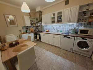 una cucina con mobili bianchi, lavatrice e asciugatrice di Vince apartman a Pécs
