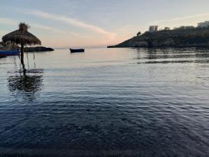 a beach with an umbrella and a boat in the water at Sea view in Sozopol +6 photos