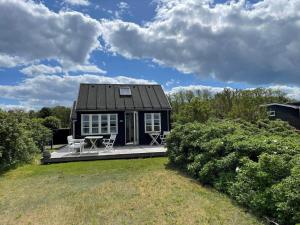 a small black house with a porch and two chairs at 40155-Juelsminde-Bugten-31 in Juelsminde