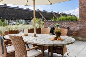 a wooden table with chairs and an umbrella on a patio at 1900-Romo-Klitrosevej-40 in Sønderby