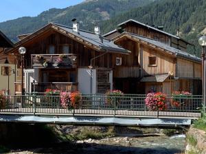 a wooden house with flowers on a bridge at Appartamento Rita in Pozza di Fassa