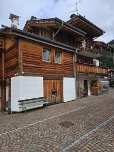a wooden building with a bench in front of it at Appartamento Rita in Pozza di Fassa