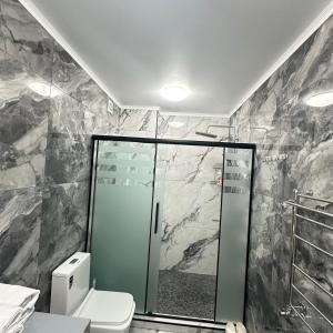 ein Badezimmer mit Glasdusche und Toilette in der Unterkunft КАРАВАН САРАЙ 15 Венеция in Türkistan + 15 Fotos