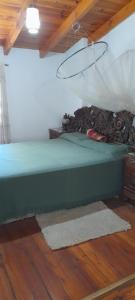 a green bed in a room with a wooden floor at El ceibo in Agua de Oro