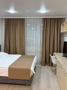 a bedroom with a bed and a desk and a television at Yes apart hotel in Astana