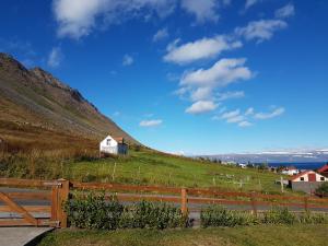 Ein Zaun auf einem Hügel mit einem Haus darauf in der Unterkunft Sigurhæð - Apartment with all within your reach in Ísafjörður