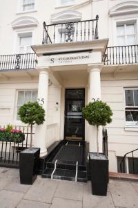 una puerta delantera de un edificio con dos macetas en St George's Inn Victoria, en Londres