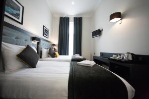 a hotel room with two beds and a window at St George's Inn Victoria in London