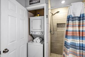 a bathroom with a washing machine and a shower at Seashell Retreat - Beachfront Condo with Pools and Cabanas in Galveston