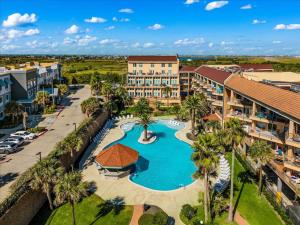 an aerial view of a resort with a pool and palm trees at Seashell Retreat - Beachfront Condo with Pools and Cabanas in Galveston