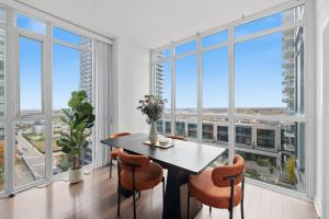 Stylish Downtown - Condo Sleeps 8 - YYZ Airport في ميسيساوغا: غرفة طعام مع طاولة وكراسي ونوافذ كبيرة